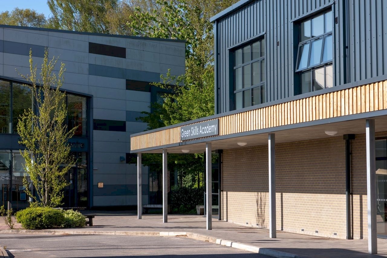 Modern Green Skills Academy building exterior with large windows and trees nearby.