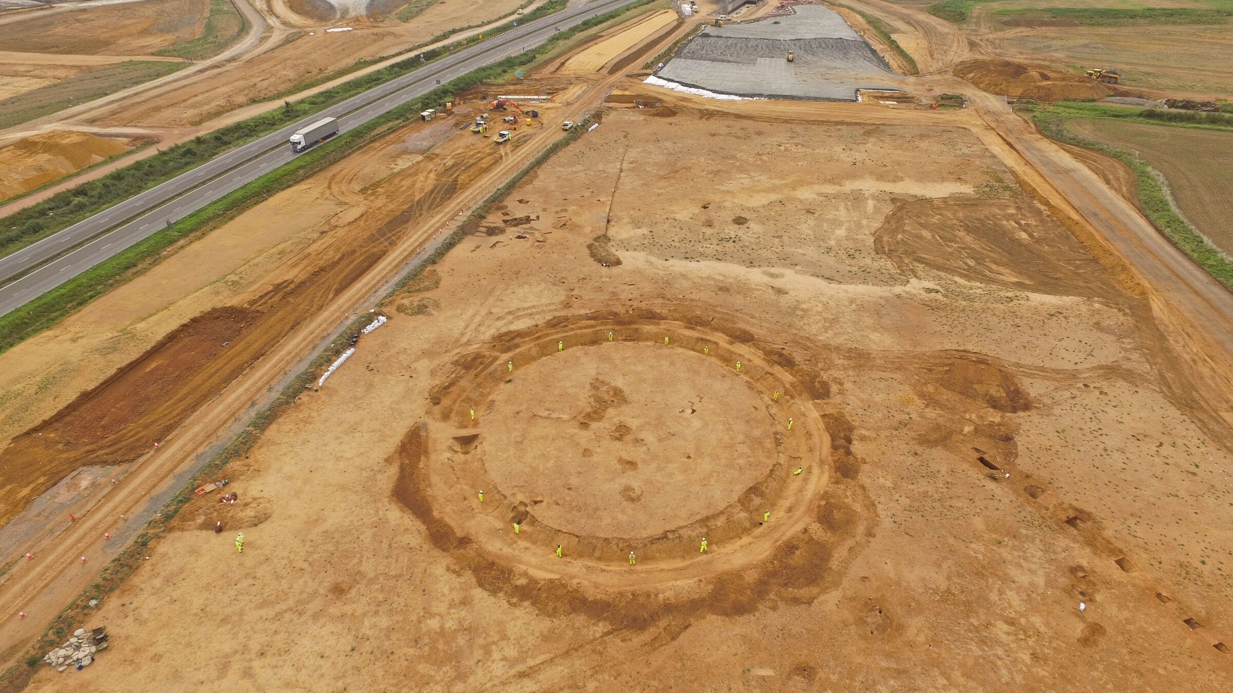 Aerial view of an archaeological site featuring a circular structure amid construction areas.