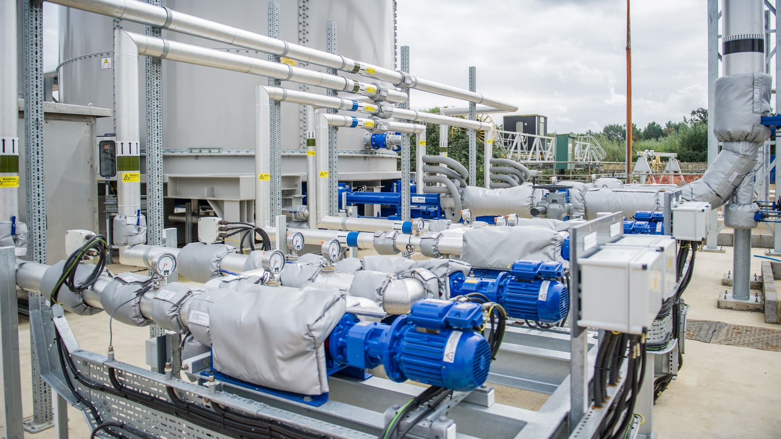 Industrial water pumps and pipelines in a modern outdoor facility with blue motors.