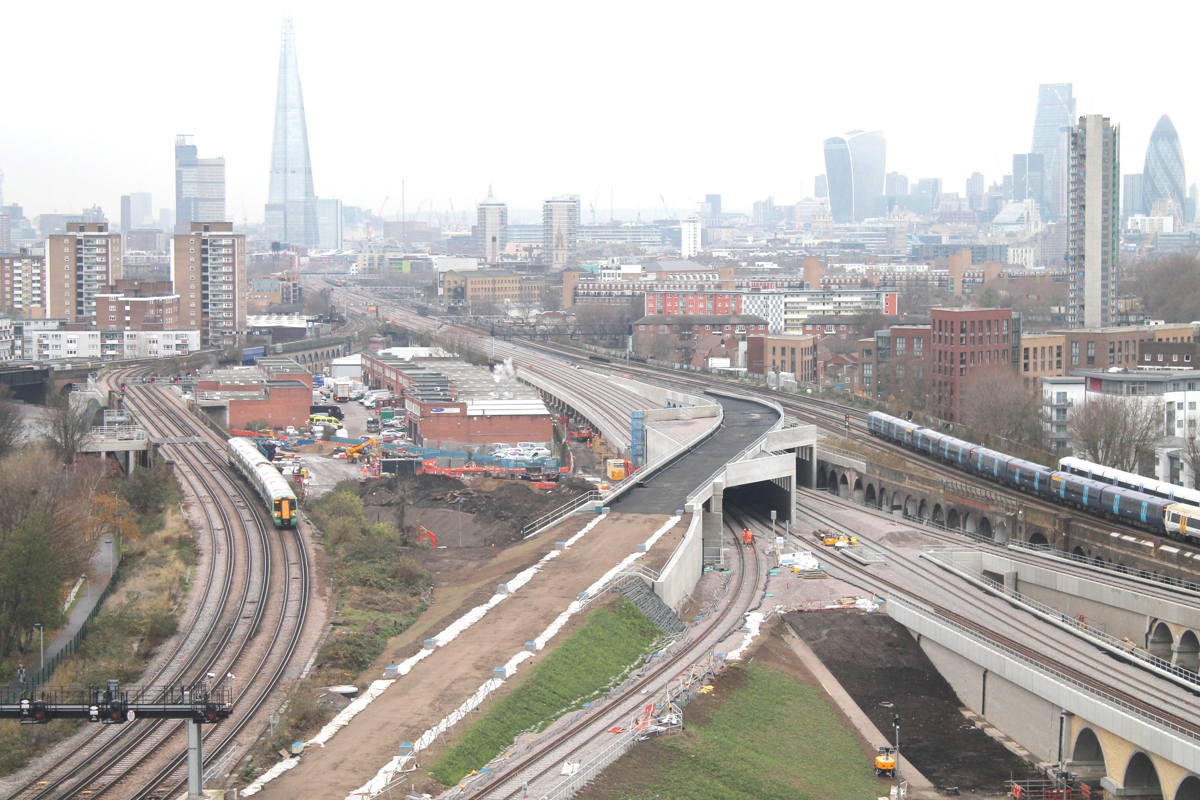 London Railway Development with City Skyline View Aerial view of railway construction in London with trains, tracks, and city skyline in the background.