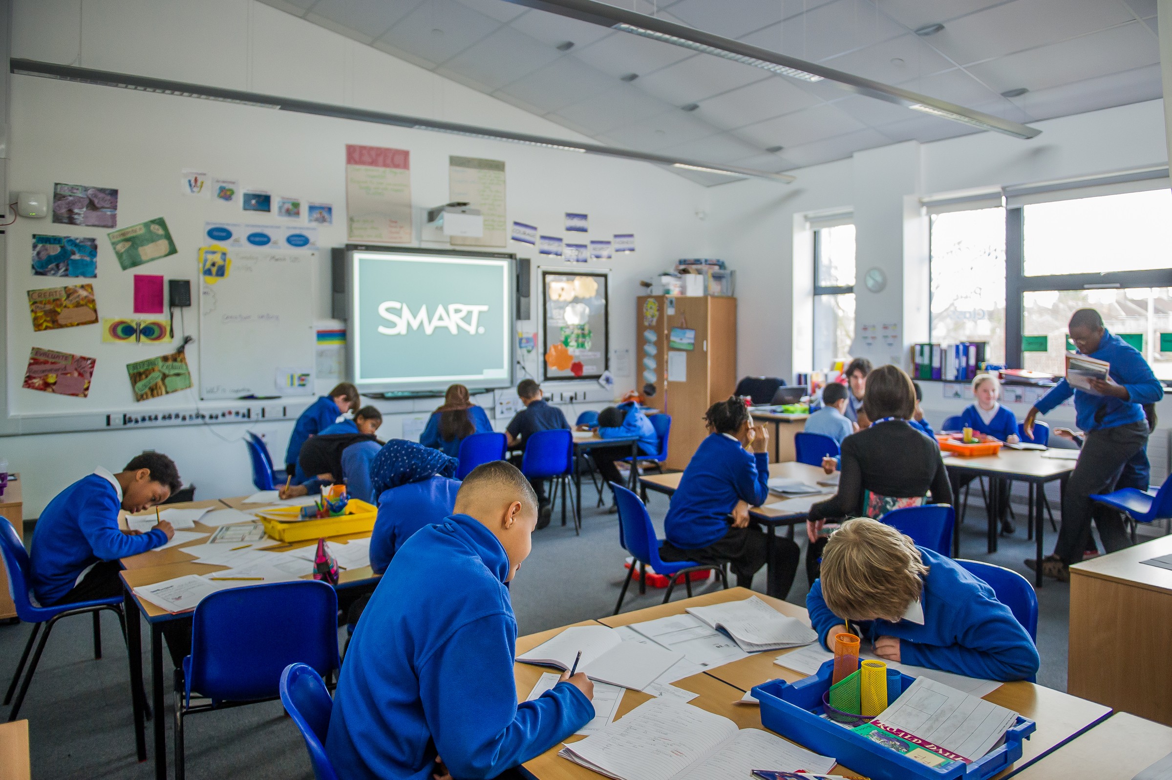 One of the bright learning spaces we created at Glenfrome Primary as part of a major refurbishment A classroom of engaged students in blue uniforms working on assignments with a SMART board in use.