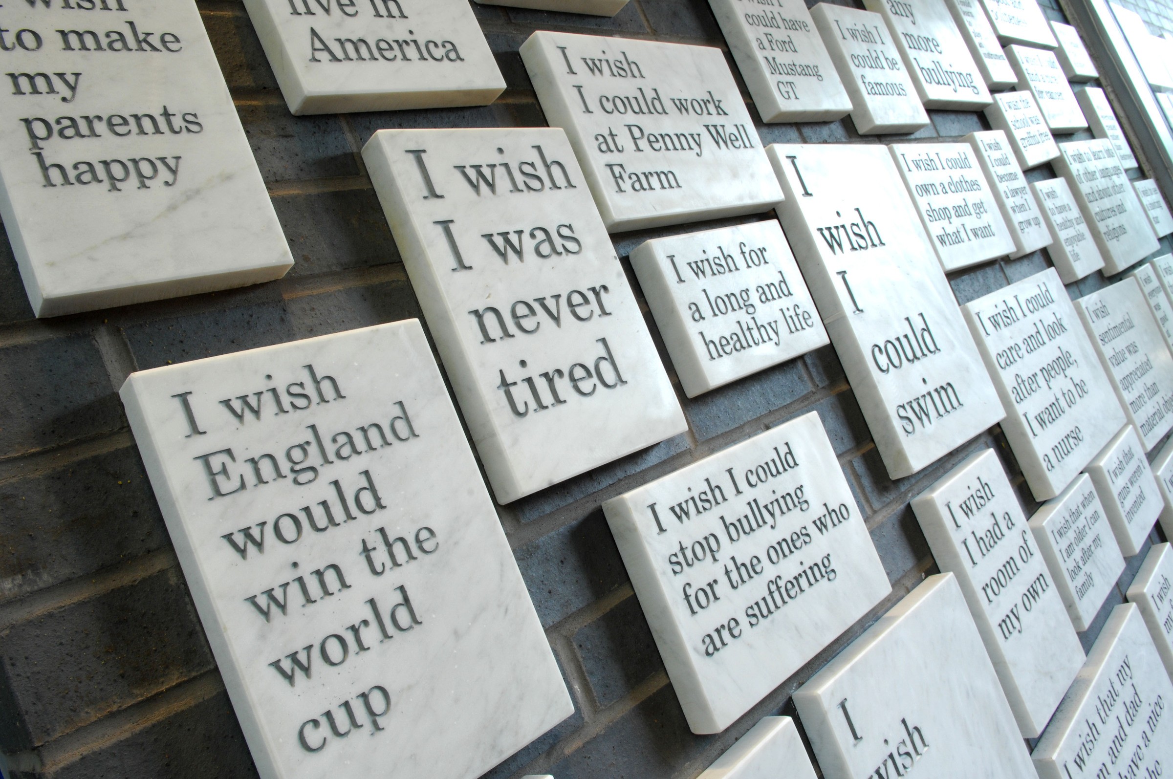 Marble plaques display various wishes, including hopes for health, happiness, and world peace.