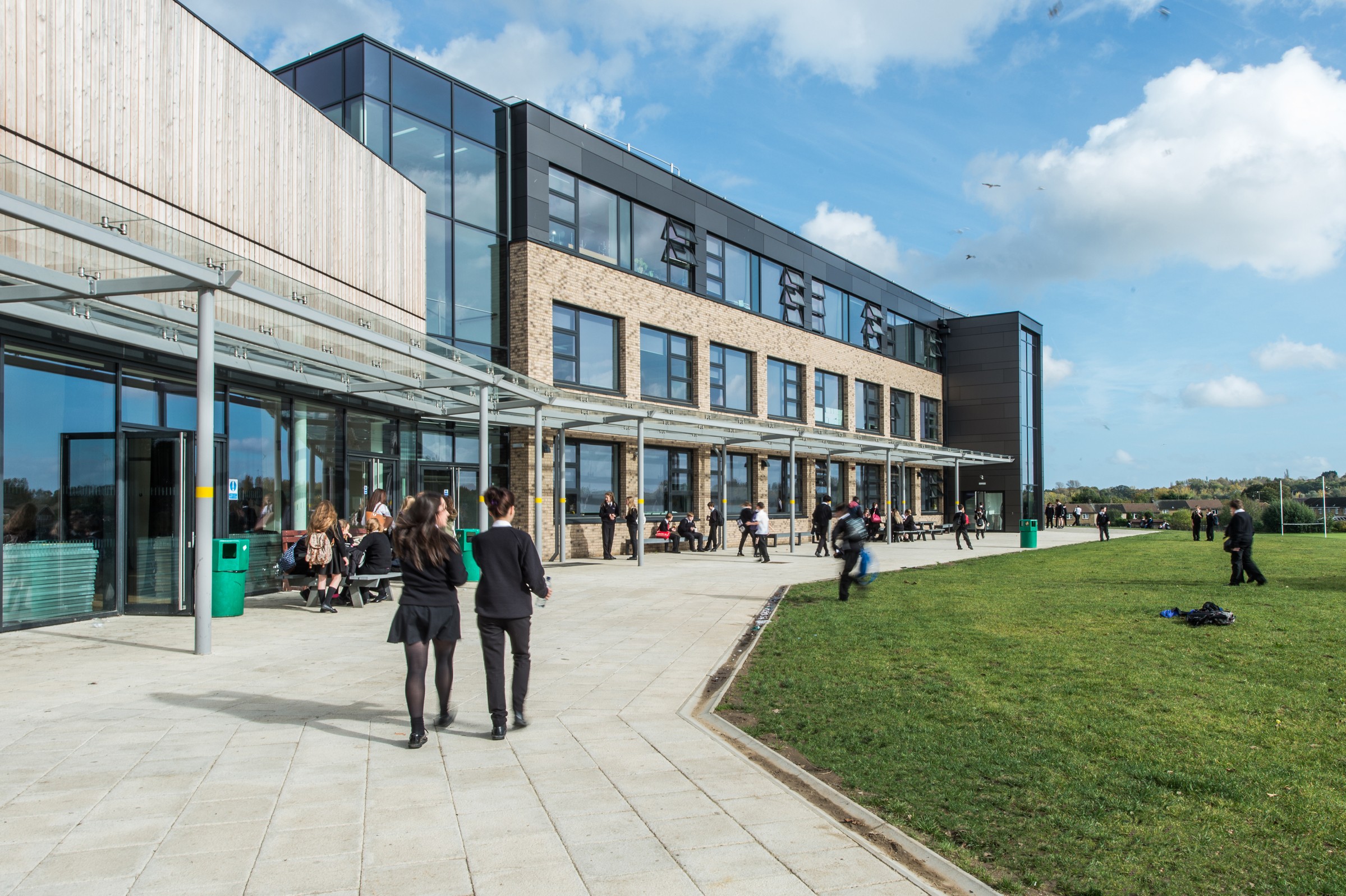 Essex Schools - Woodlands School Modern school building with students walking and sitting outside on a sunny day.
