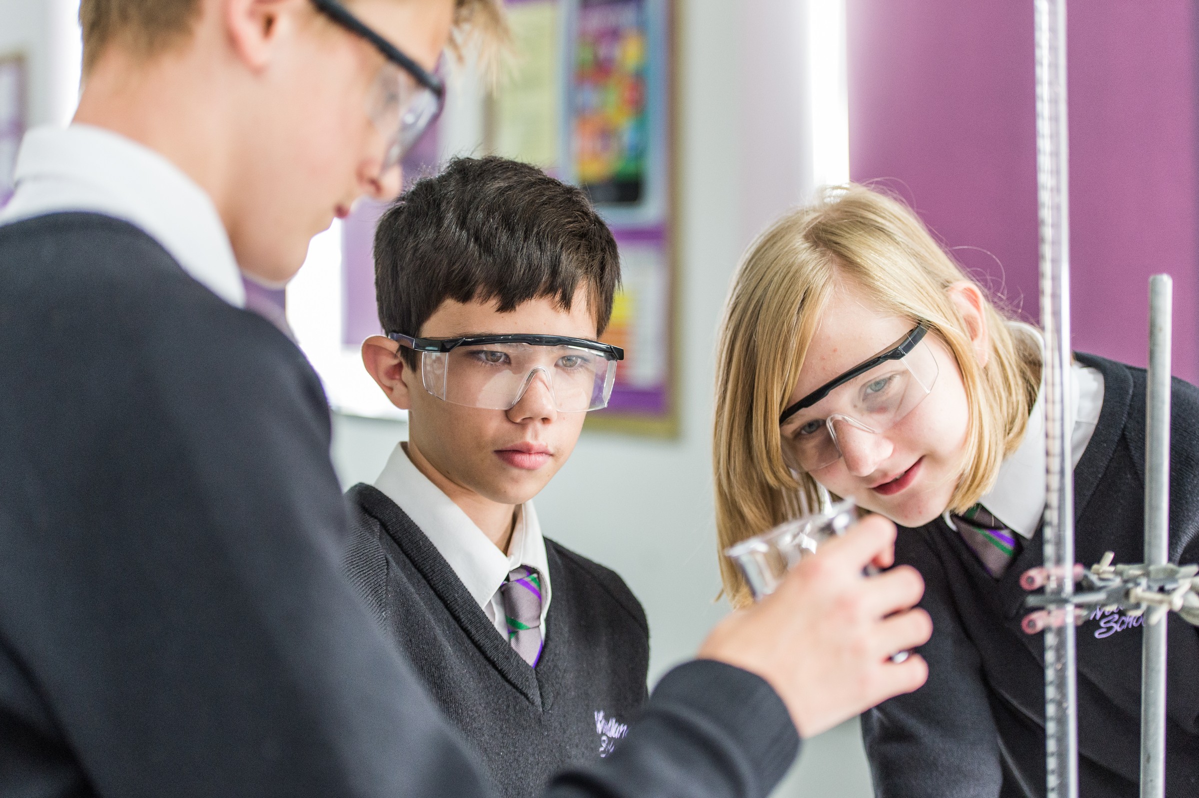 Essex Schools - Woodlands School Students in uniform conduct a science experiment in a classroom setting, focusing on teamwork.