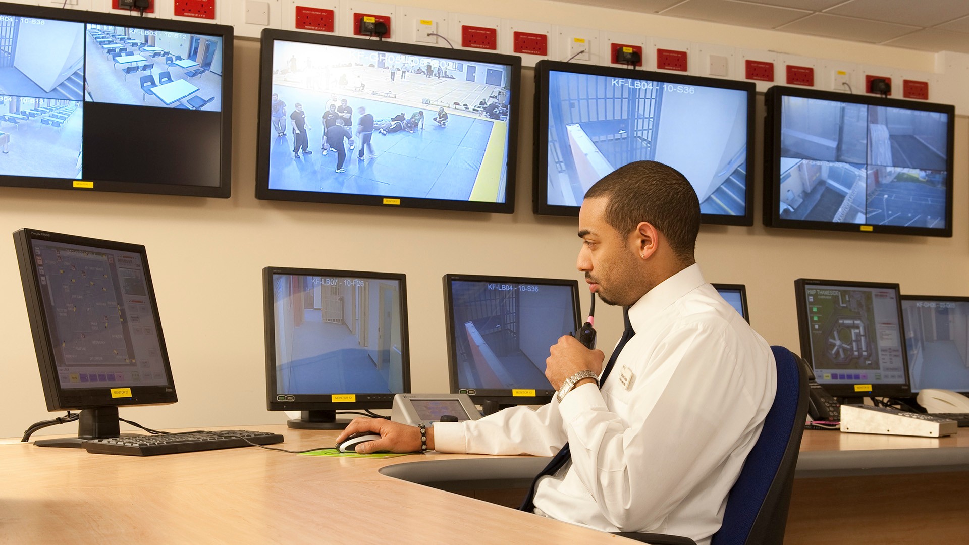 Security officer monitors multiple CCTV screens in a control room, ensuring public safety.