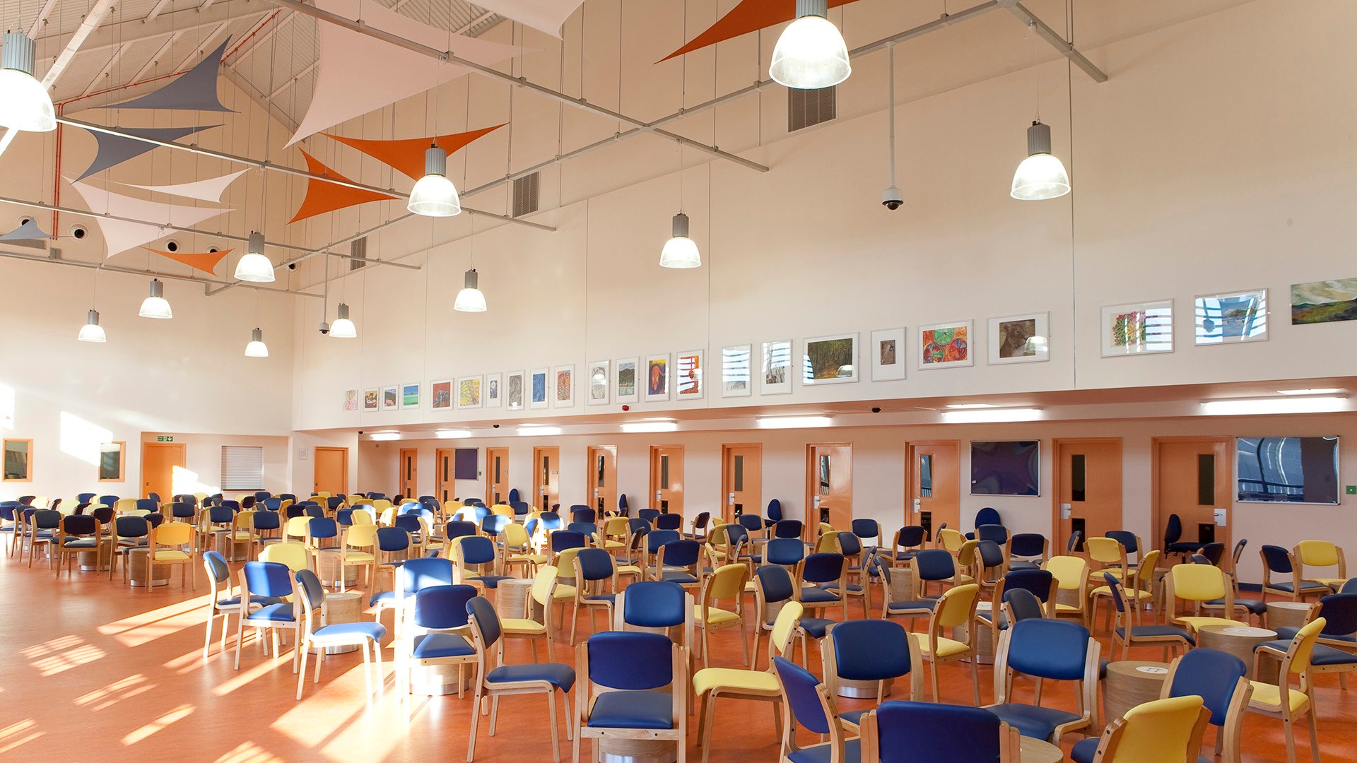 Large, brightly lit community hall with colorful chairs and vibrant wall art.