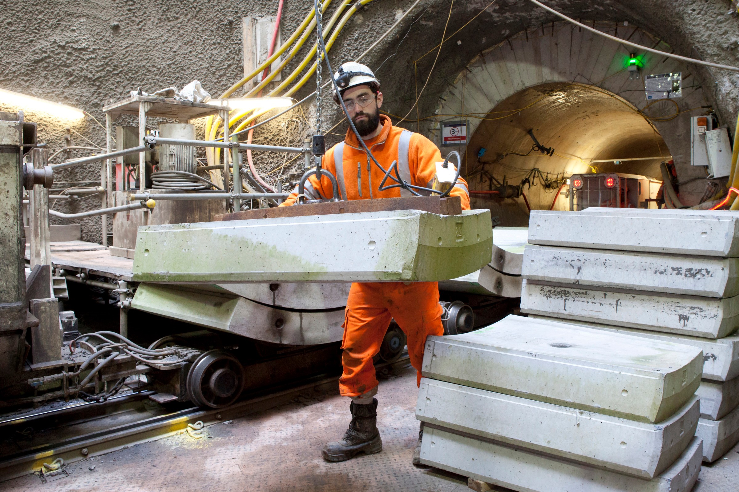 Tunnel Construction Worker Handling Concrete Slabs Construction worker in an underground tunnel handling large concrete slabs in safety gear.