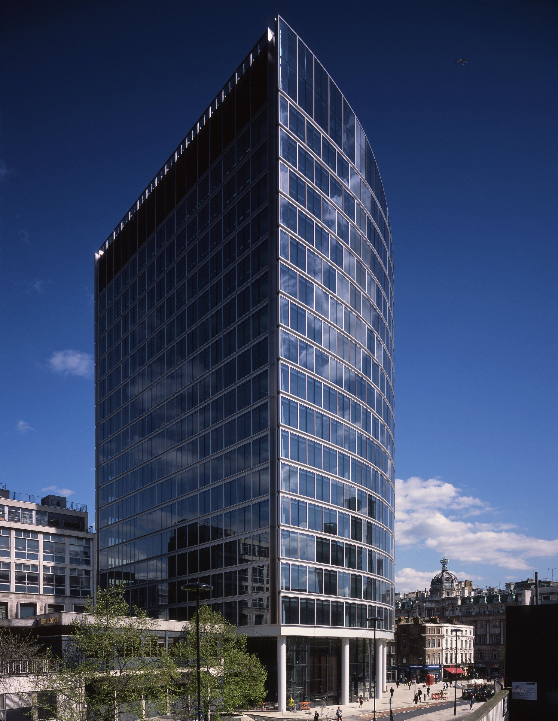 Modern glass office building against a clear blue sky, showcasing urban architecture in daylight.