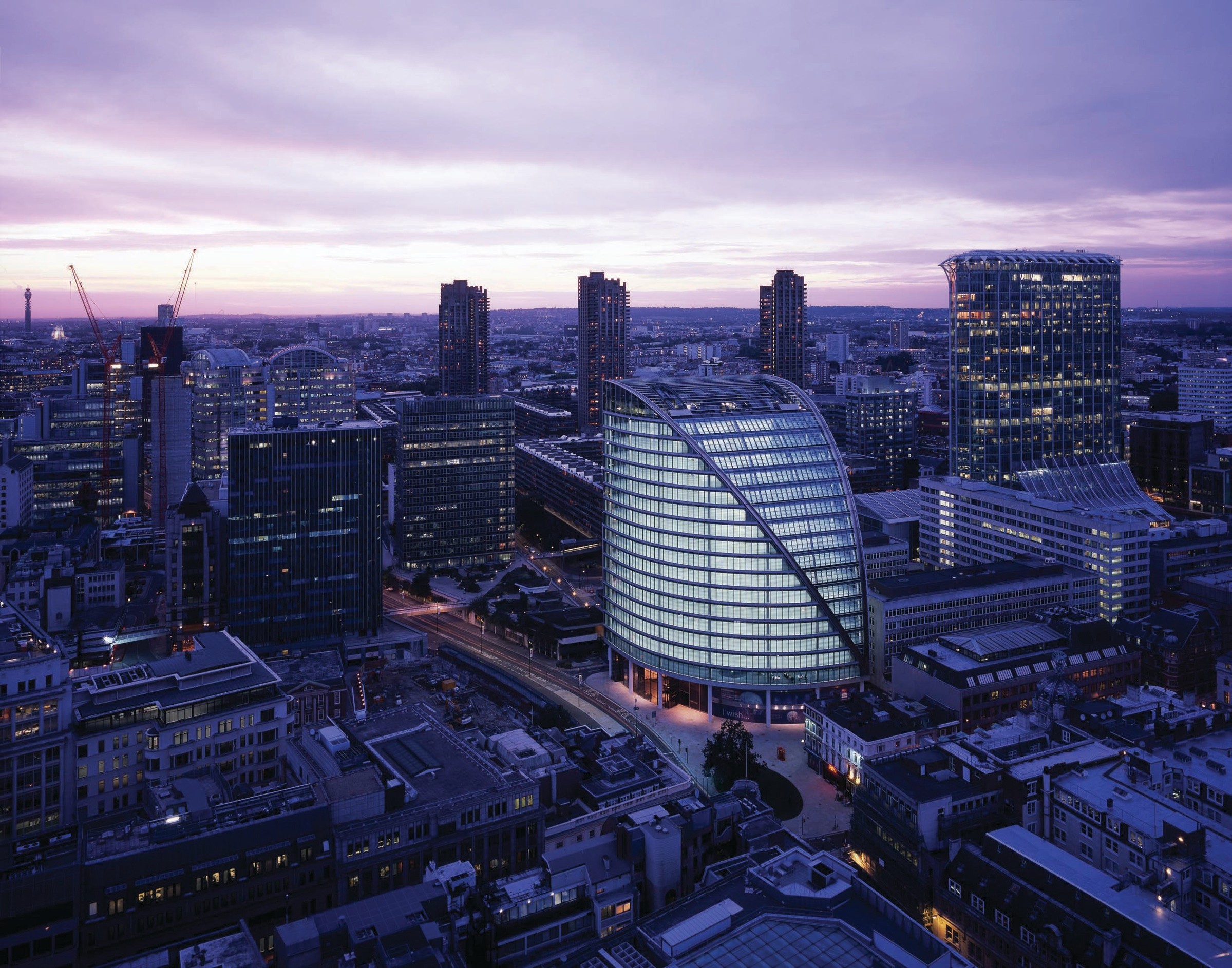 Aerial view of London cityscape at dusk, featuring modern architecture and illuminated buildings.