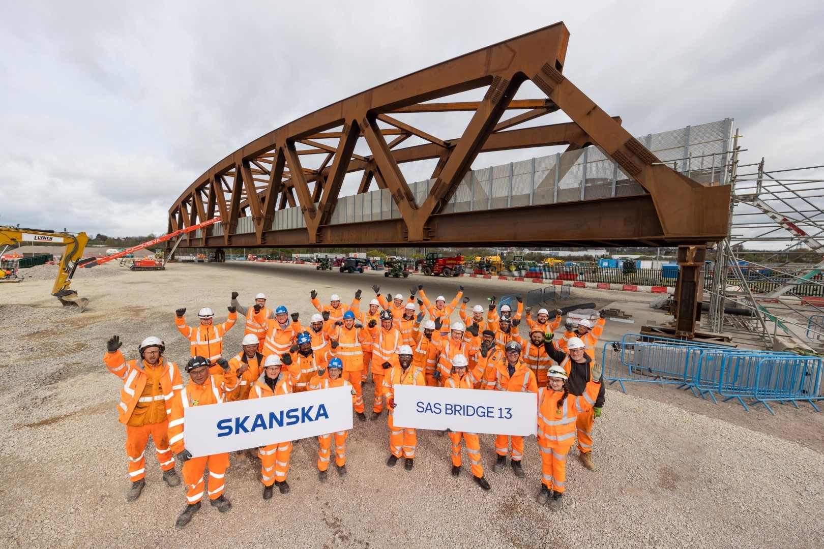 Construction team celebrating completion of SAS Bridge 13, with Skanska signage in foreground.