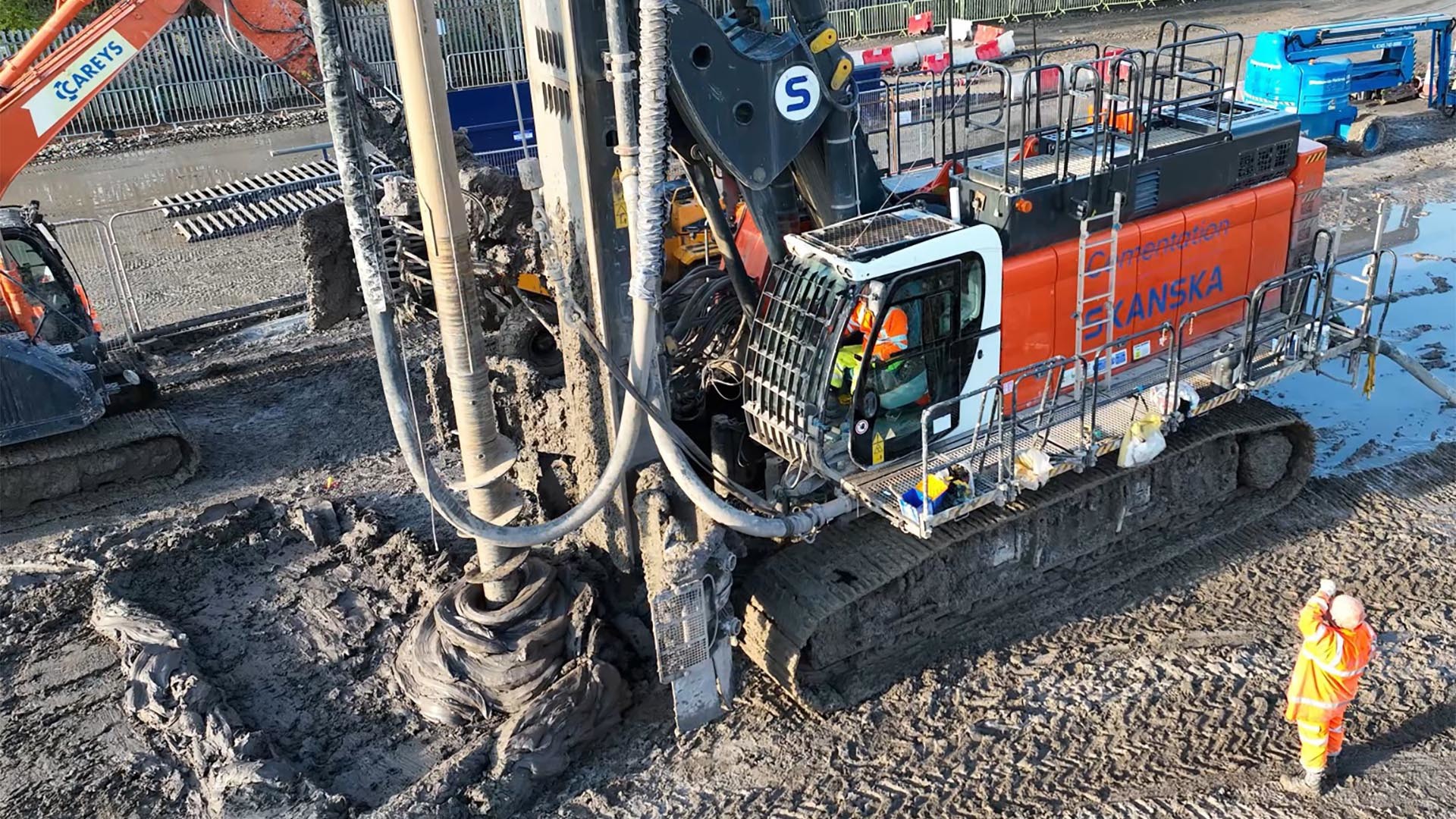 CFA piling rig at work Construction site with heavy machinery drilling into the muddy ground, supervised by workers in safety gear.