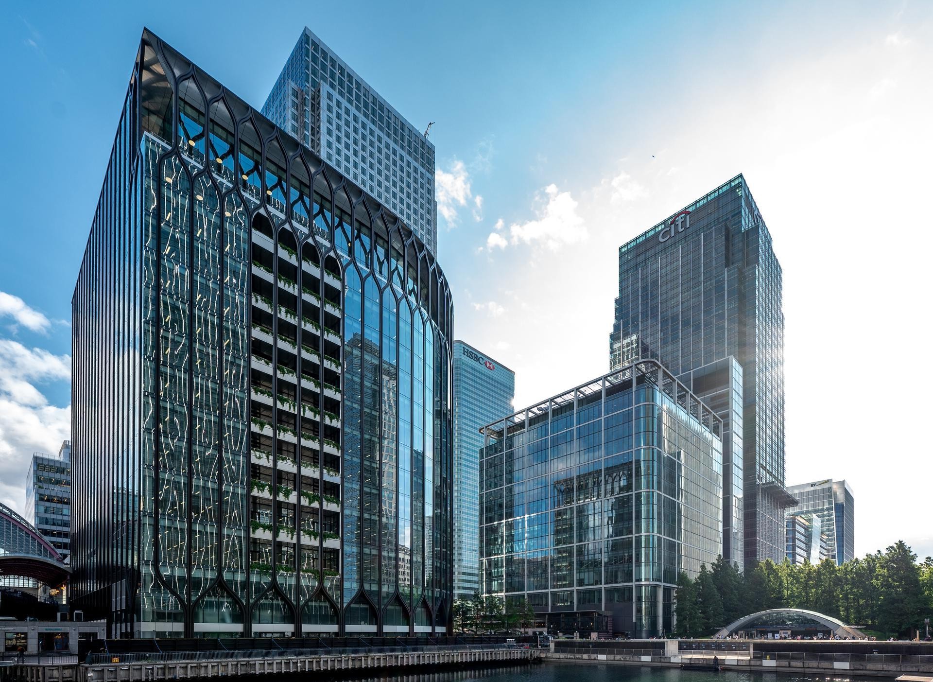 Modern skyscrapers in a business district with glass facades reflecting the sky and surroundings.