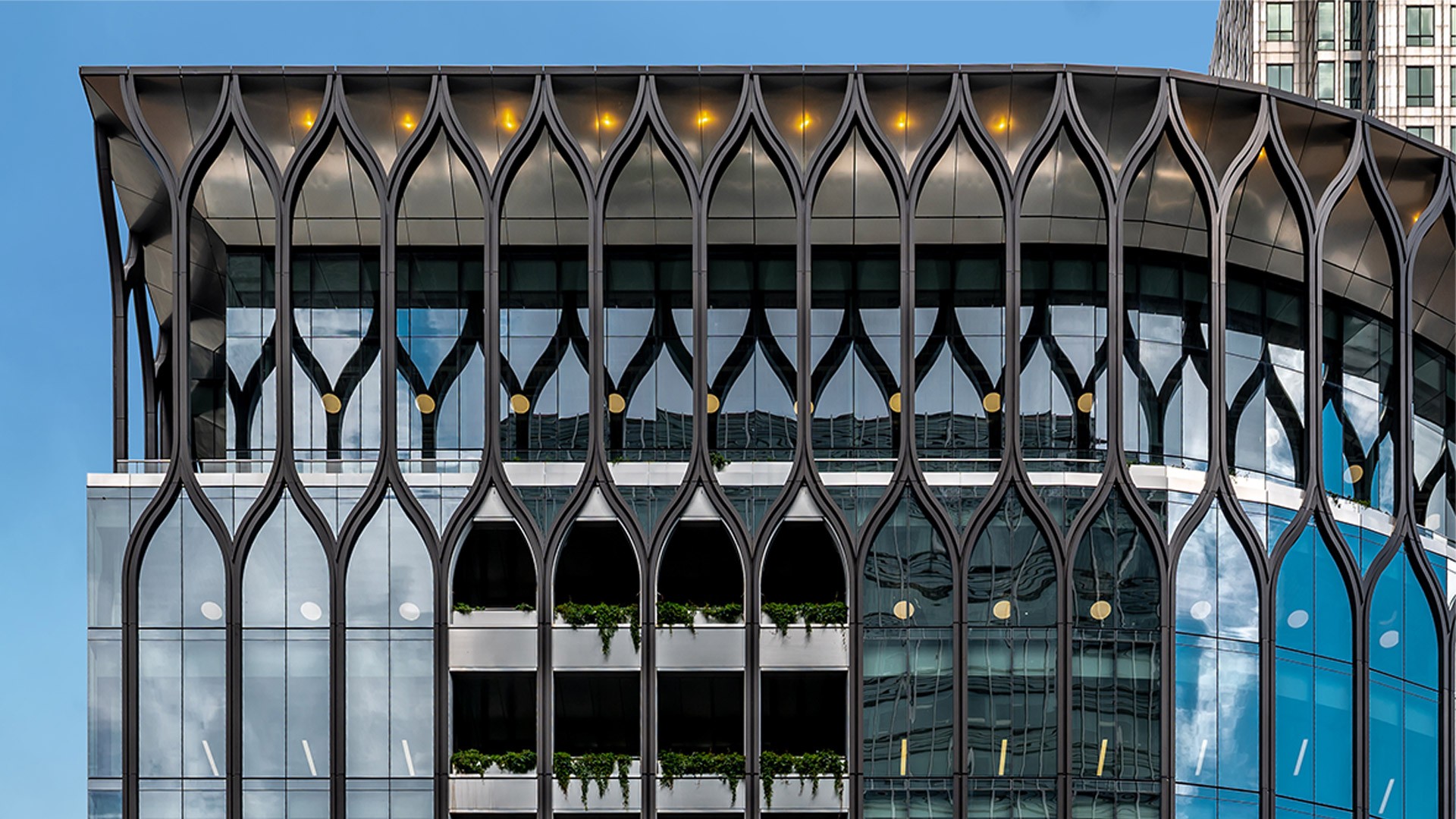 Modern building facade with intricate geometric patterns and reflective glass windows.