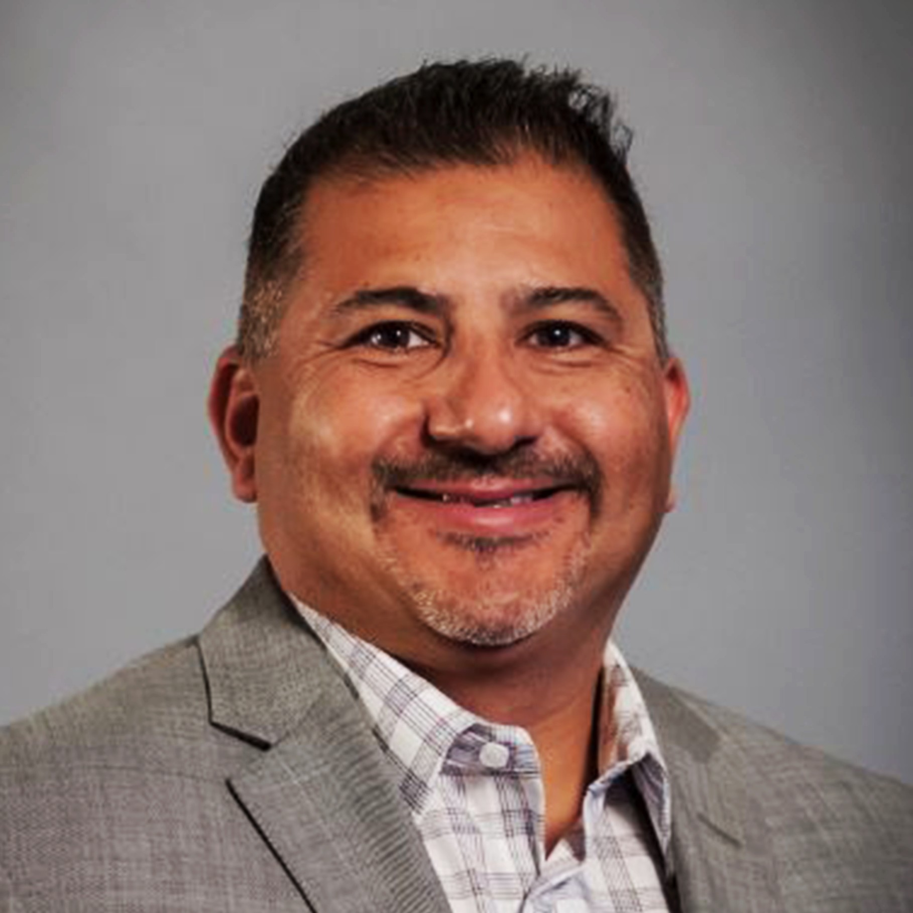Professional Man in Gray Suit and Checkered Shirt Portrait Man in gray suit jacket and checkered shirt against a plain gray background.