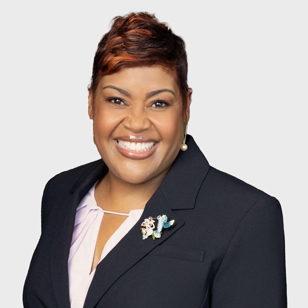 Professional Woman in Business Attire with Stylish Brooch A person in a dark blazer with a decorative butterfly brooch and a light-colored blouse.