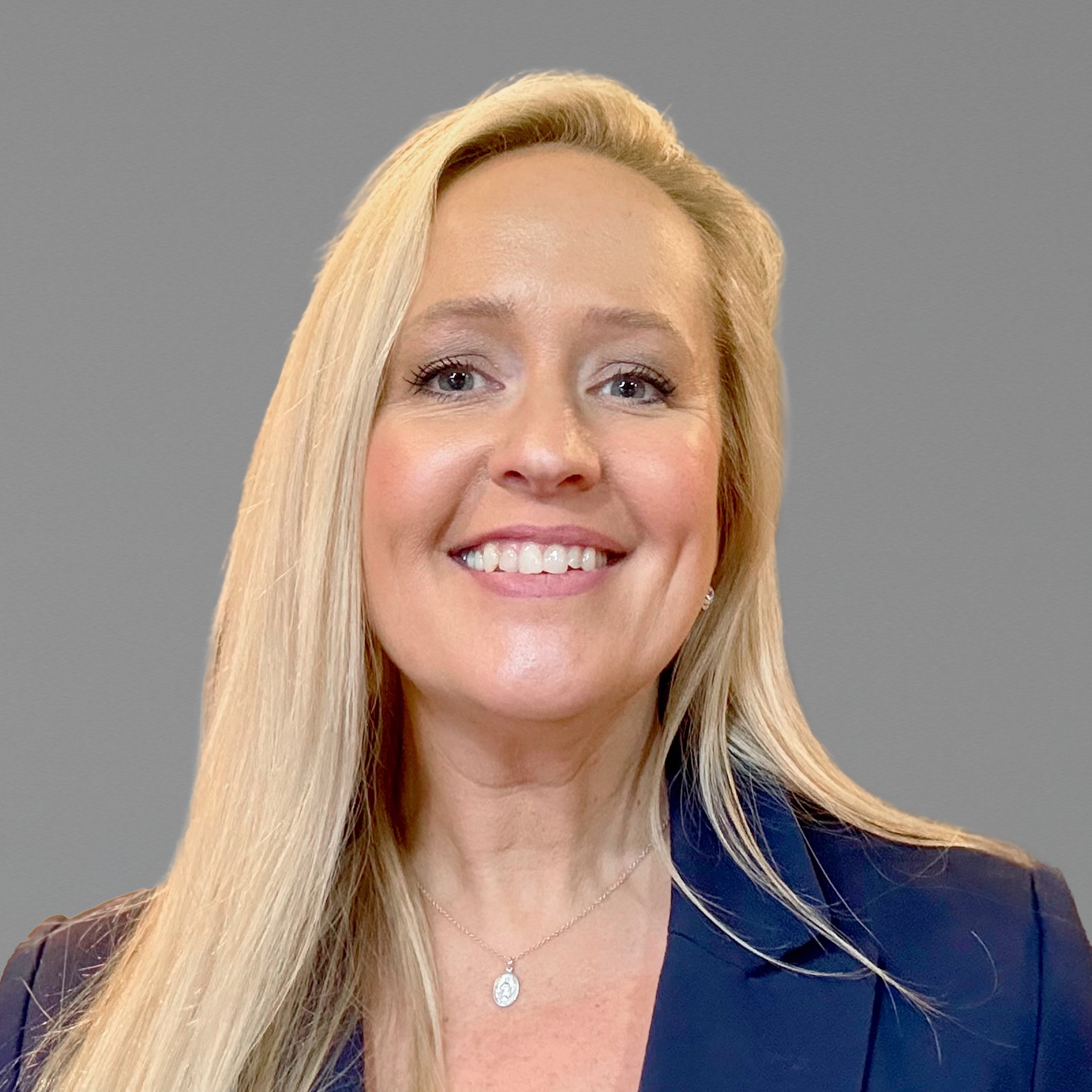 Professional woman with long blonde hair in navy blazer Becky wearing a navy blazer against gray background.