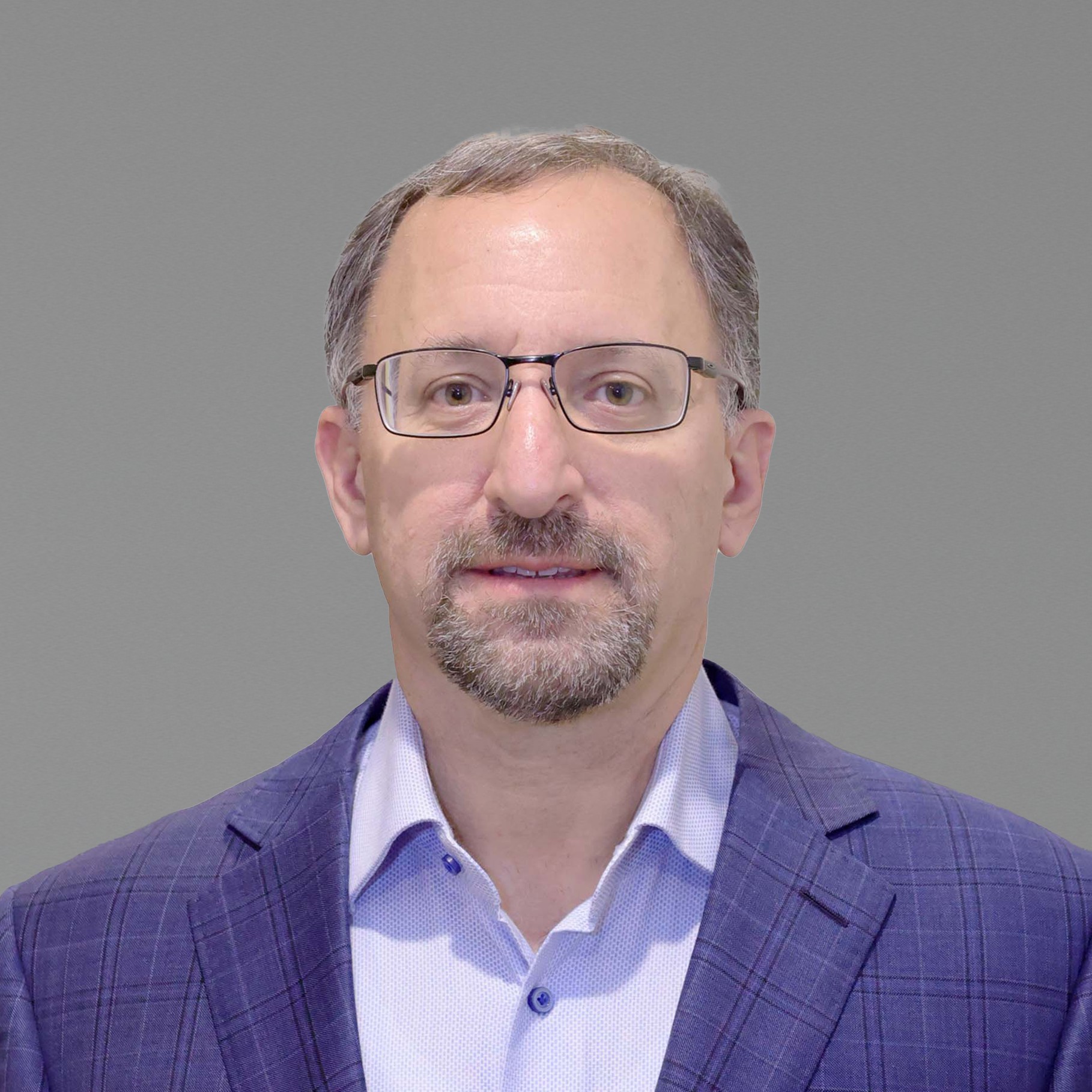 Professional man in blue checkered suit jacket on gray background Andrew in a blue checkered blazer and light blue shirt against a gray background.