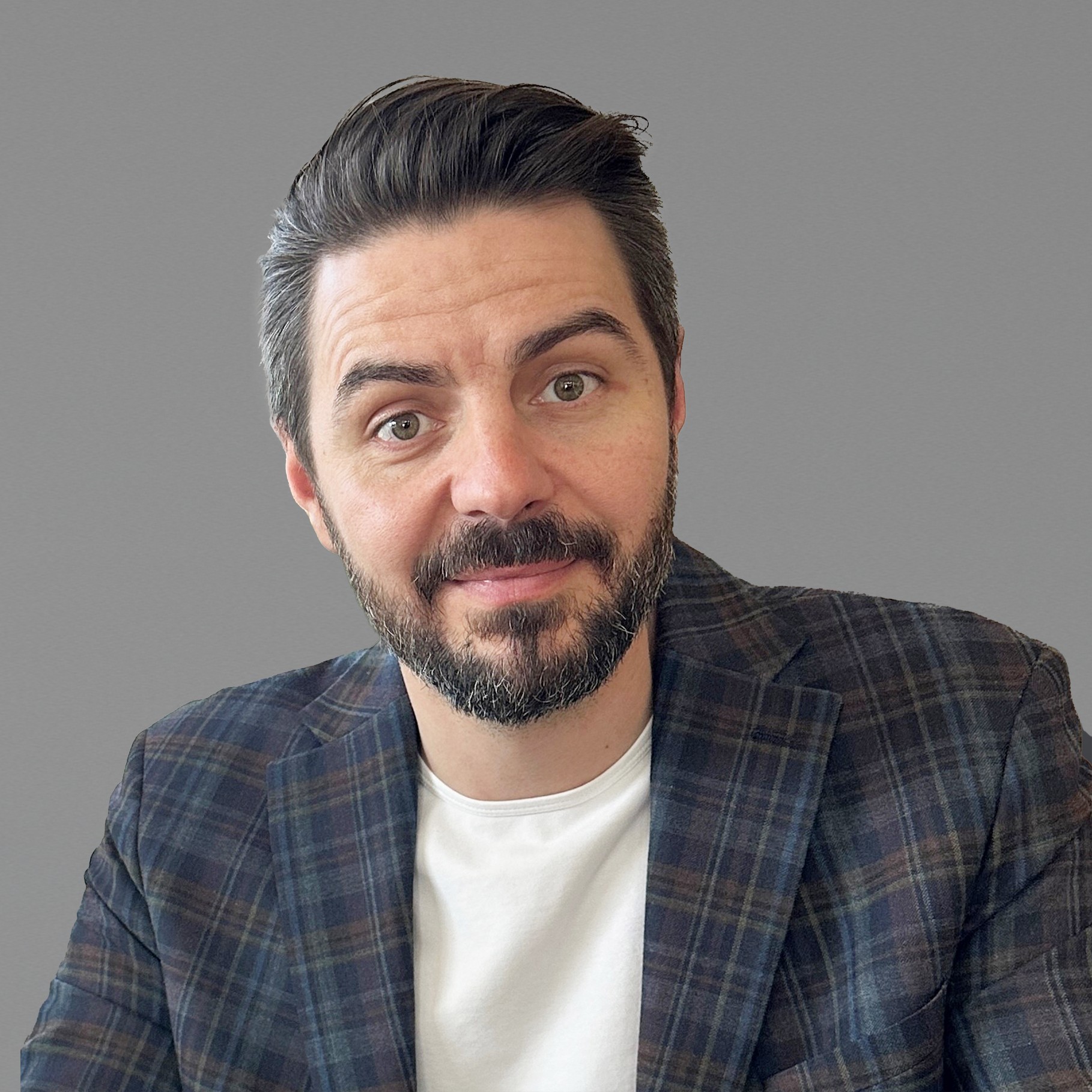 Man in Casual Plaid Blazer and White T-Shirt on Gray Background Zac in a plaid blazer and white shirt against a plain gray background.