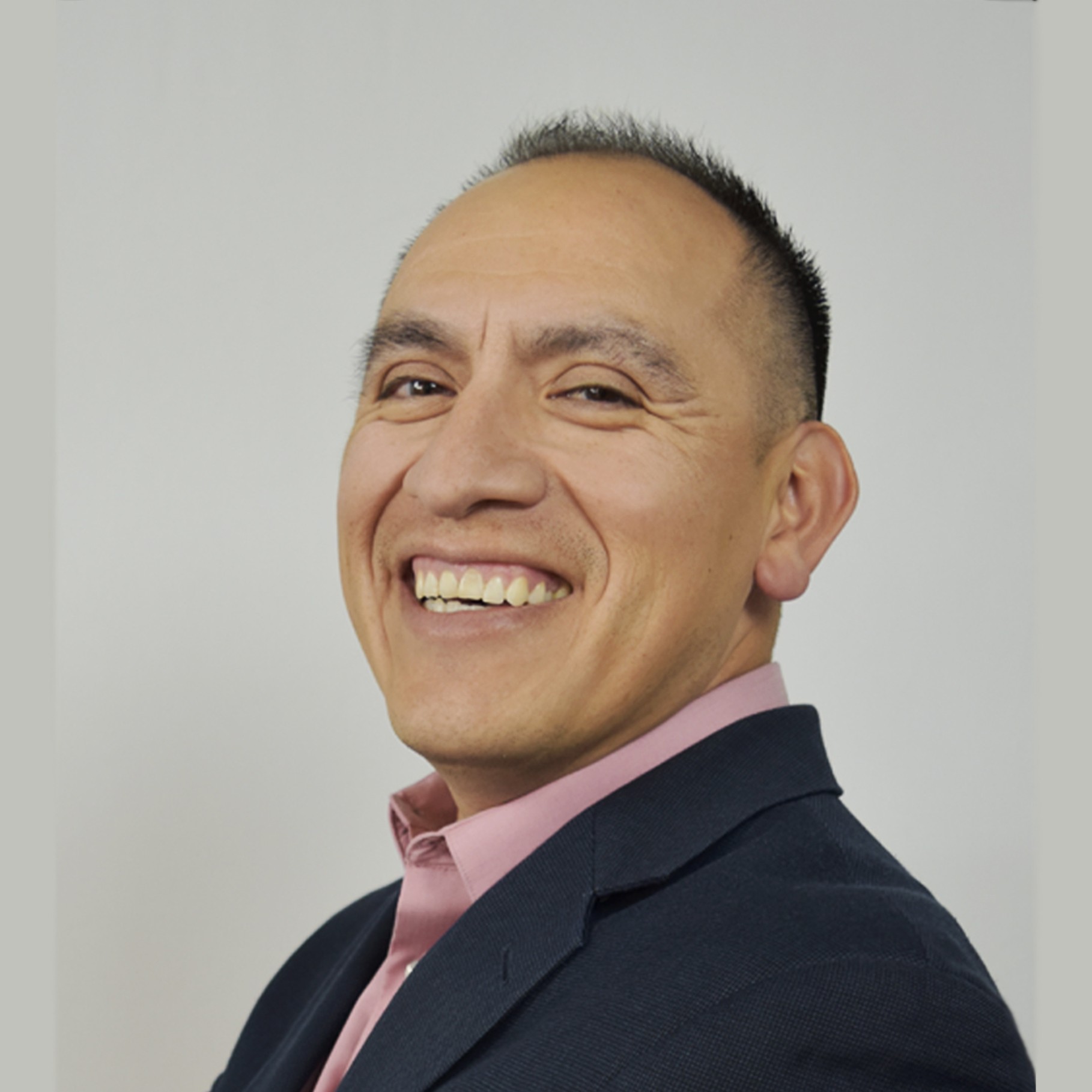 Professional Attire: Man in Suit and Pink Shirt. A person in a navy blazer and pink shirt standing against a neutral background.