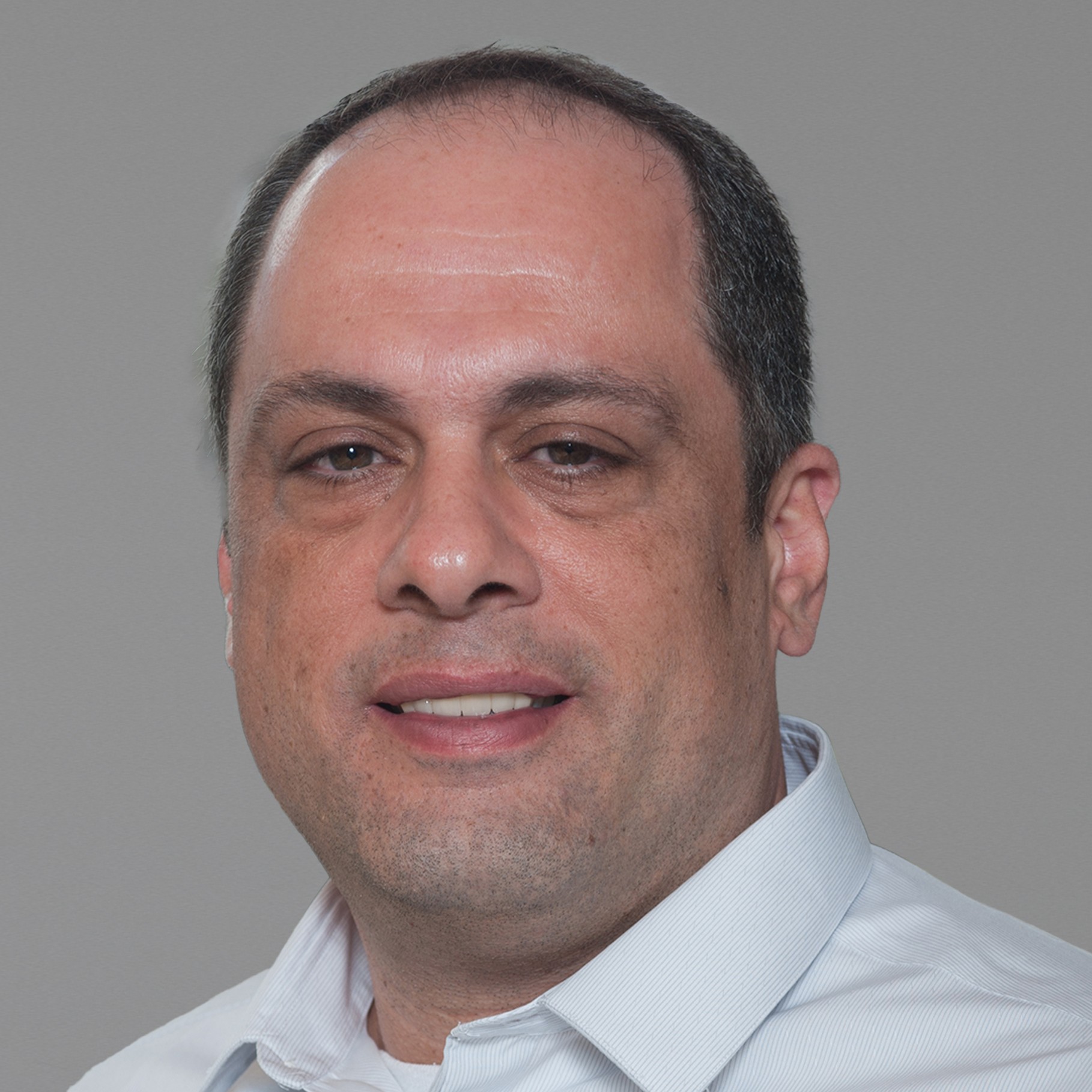 Joe Maninio - Vice President, EHS USA Civil - East Joe in a white dress shirt standing outdoors with a fountain and palm trees in the background.