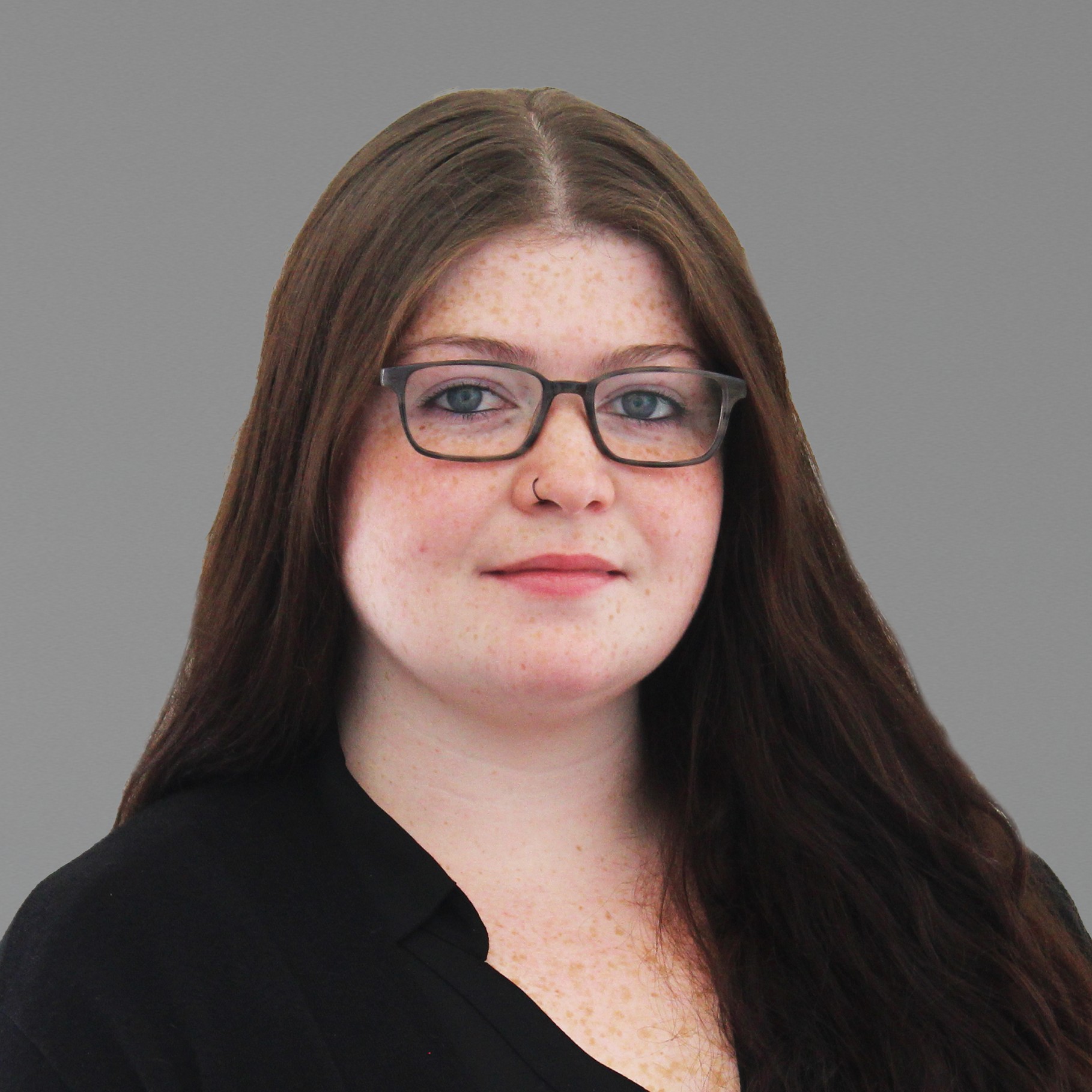Professional woman with long brown hair wearing black blouse Meagan wearing a black top against a white background.
