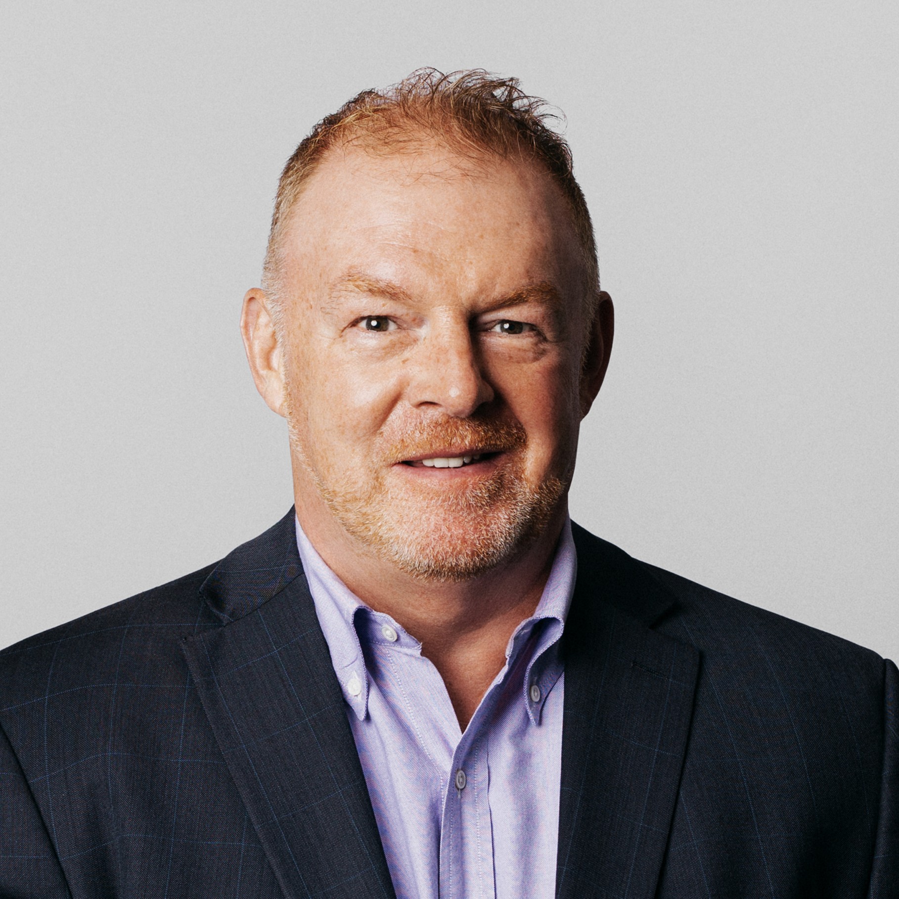 Paul in a suit and white shirt against a light background Professional Man in Suit Against Neutral Background