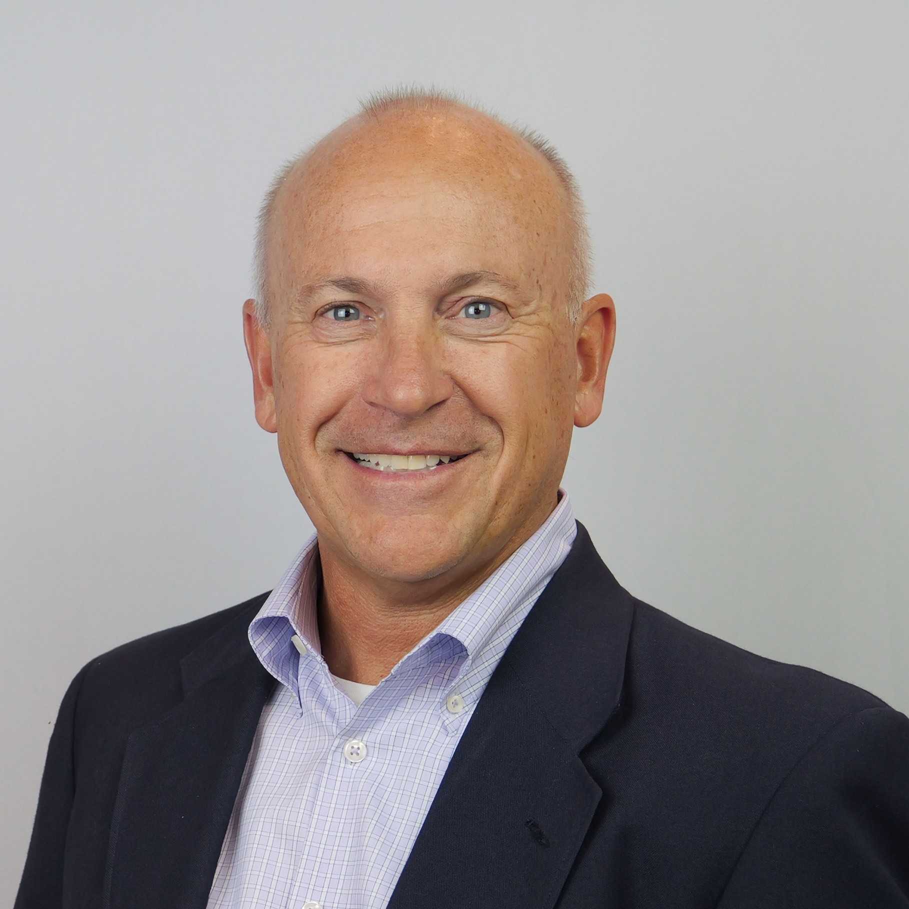 Professional Attire: Man in Suit and Collared Shirt A man in a suit jacket and collared shirt stands against a neutral background.