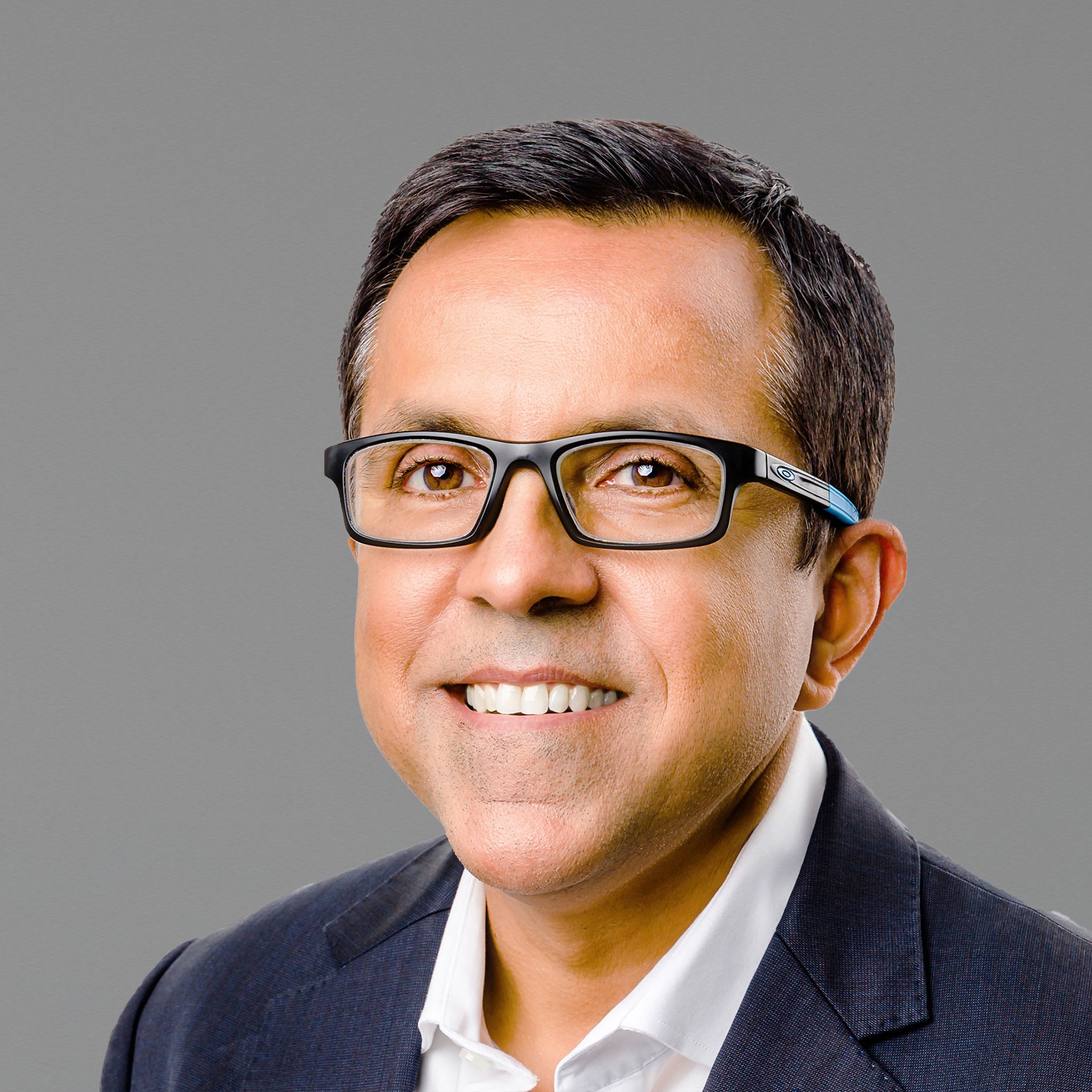 Professional Man in Suit and Glasses on White Background Ravi in a dark suit and white shirt, wearing glasses, with short dark hair.