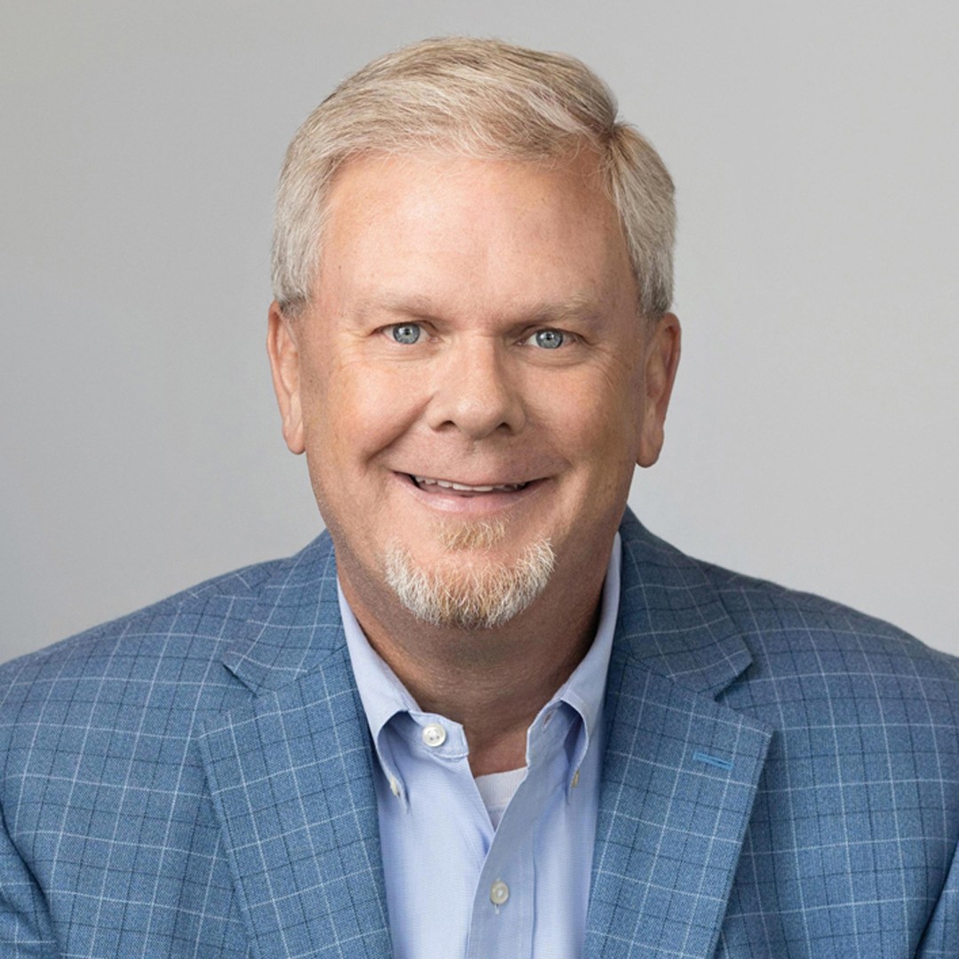 Professional man in blue checkered blazer and light blue shirt Portrait of a man in a blue checkered blazer and light blue shirt against a gray background.