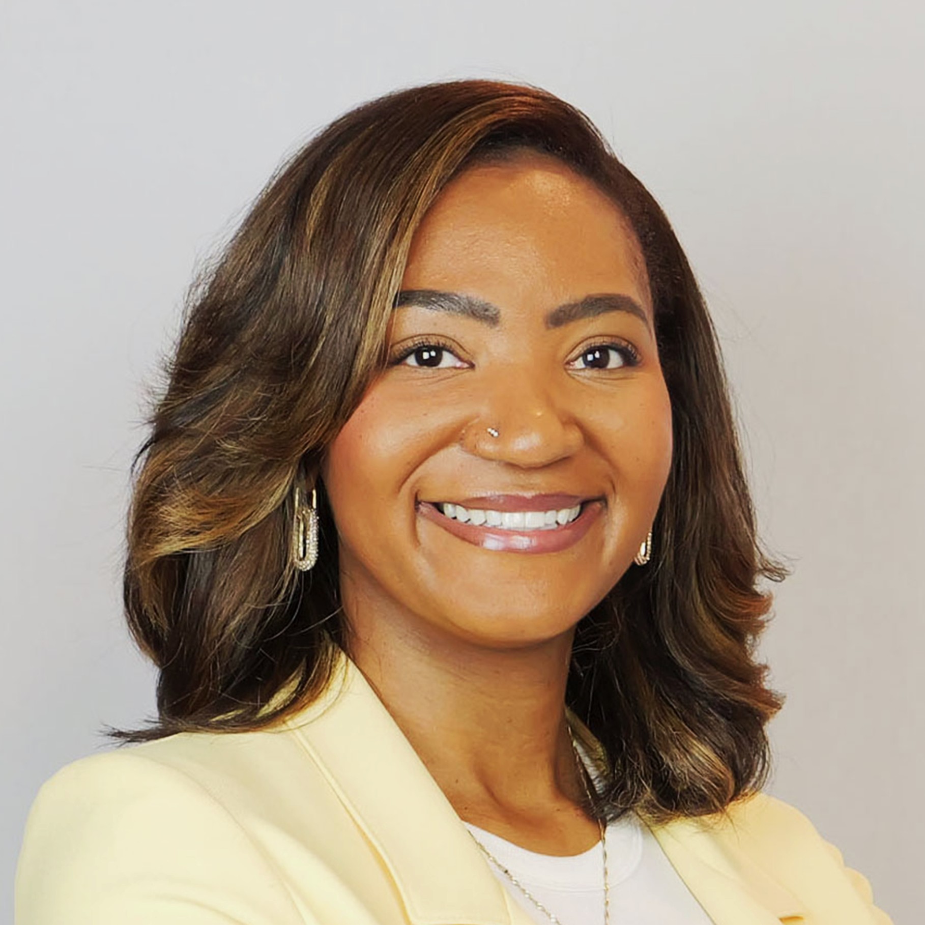 Professional woman with shoulder-length brown hair wearing a cream blazer and earrings.