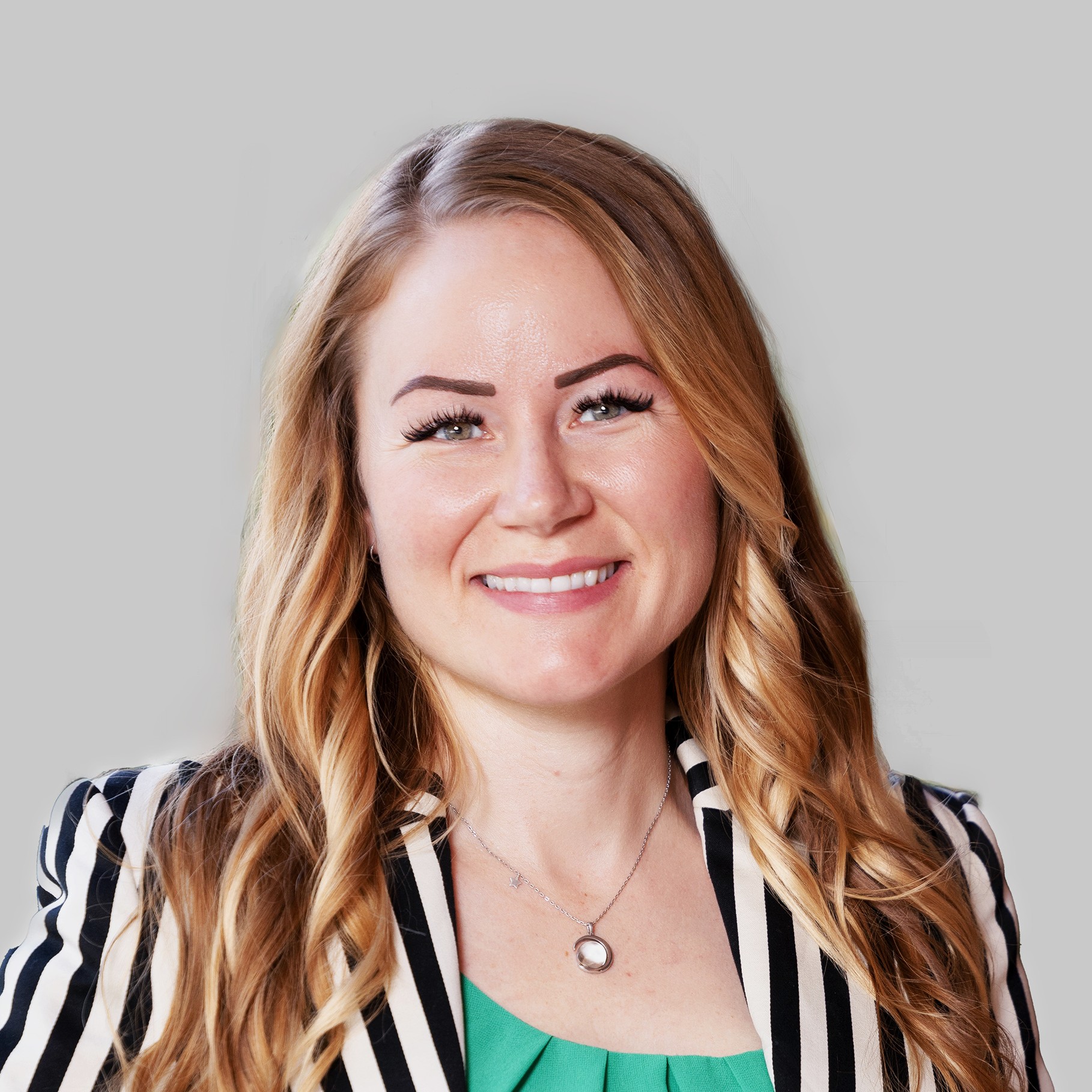 Professional woman with long blonde hair wearing a striped blazer and green top.