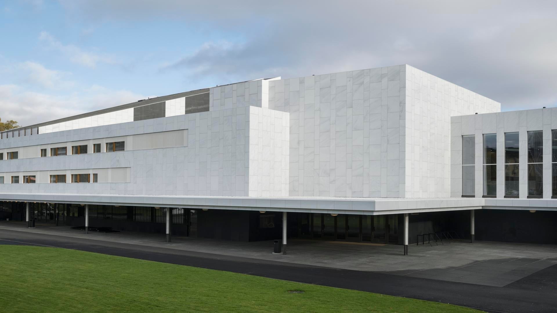 Modern white building with geometric design, large windows, and spacious exterior.