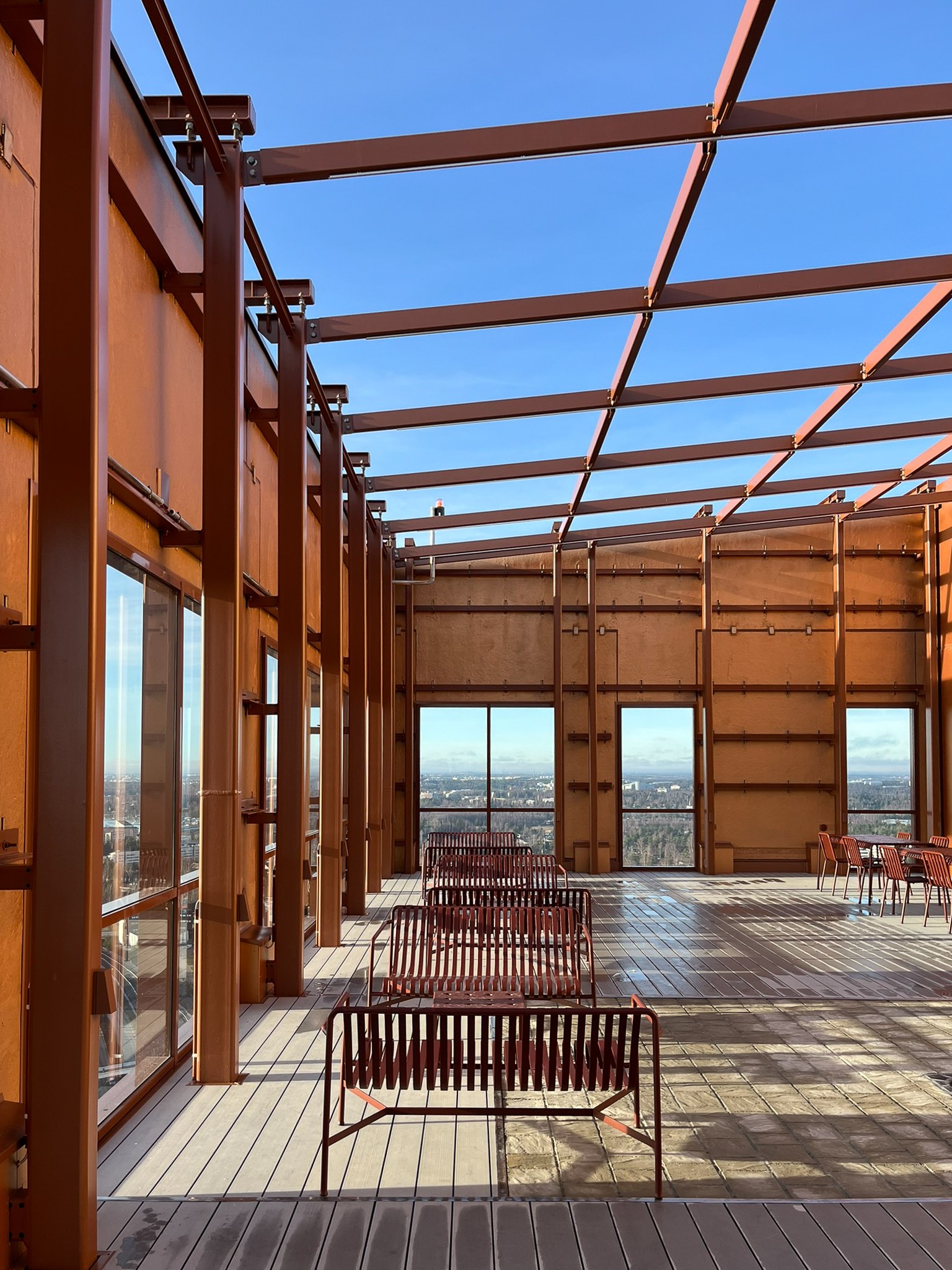 From Atlaksen rooftop terrace, there are stunning views of the sea. Rooftop terrace with rust-colored metal beams, seats, and large windows overlooking the cityscape.