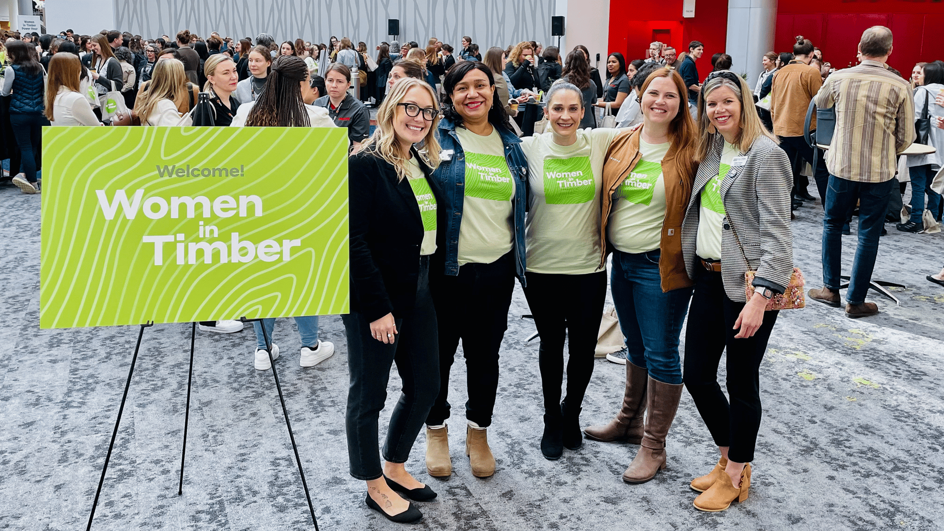 Group of women at a Women in Timber event wearing matching shirts and standing indoors.
