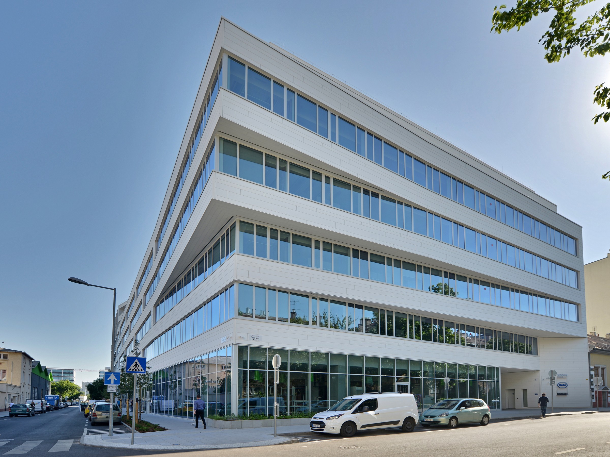 Modern office building with large glass windows on a corner street, featuring sleek architecture.