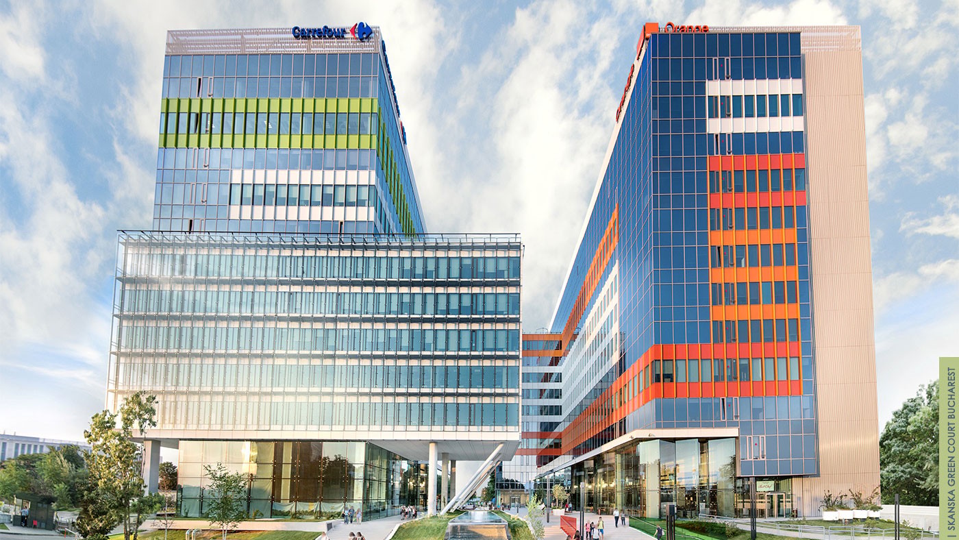 Green Court Bucharest Modern office buildings with colorful facades under a clear blue sky, featuring Carrefour and Orange logos.