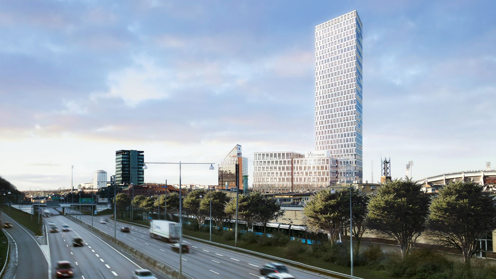 Modern skyscraper towering over a busy highway, surrounded by trees and urban buildings.