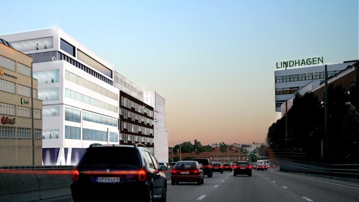 Busy highway with cars and modern buildings, including one labeled "Lindhagen," during sunset.
