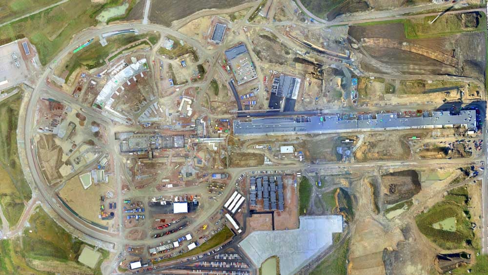 Aerial view of a large construction site featuring circular and linear structures amidst equipment.