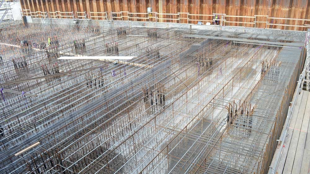 Construction site with steel rebar framework for concrete foundation reinforcement.