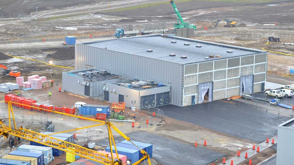 A construction site featuring a large industrial building surrounded by machinery and materials.