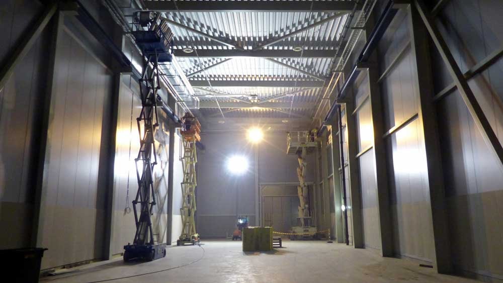 Industrial warehouse with workers on elevated platforms under bright lighting.