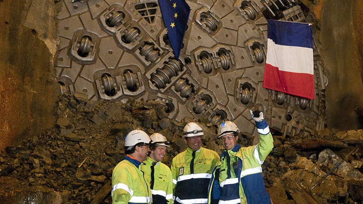 Hallandsås Workers stand in front of a large tunnel boring machine adorned with European and French flags.