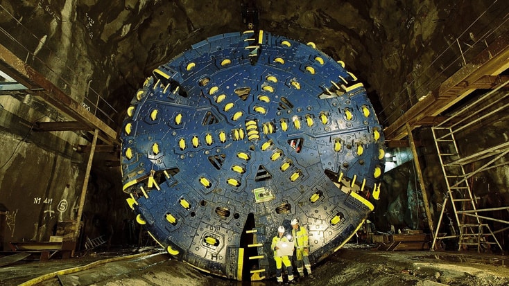 Hallandsås Tunnelbohrmaschine auf einer unterirdischen Baustelle mit Arbeitern zur Größenvergleich, präsentiert Ingenieurwesen.