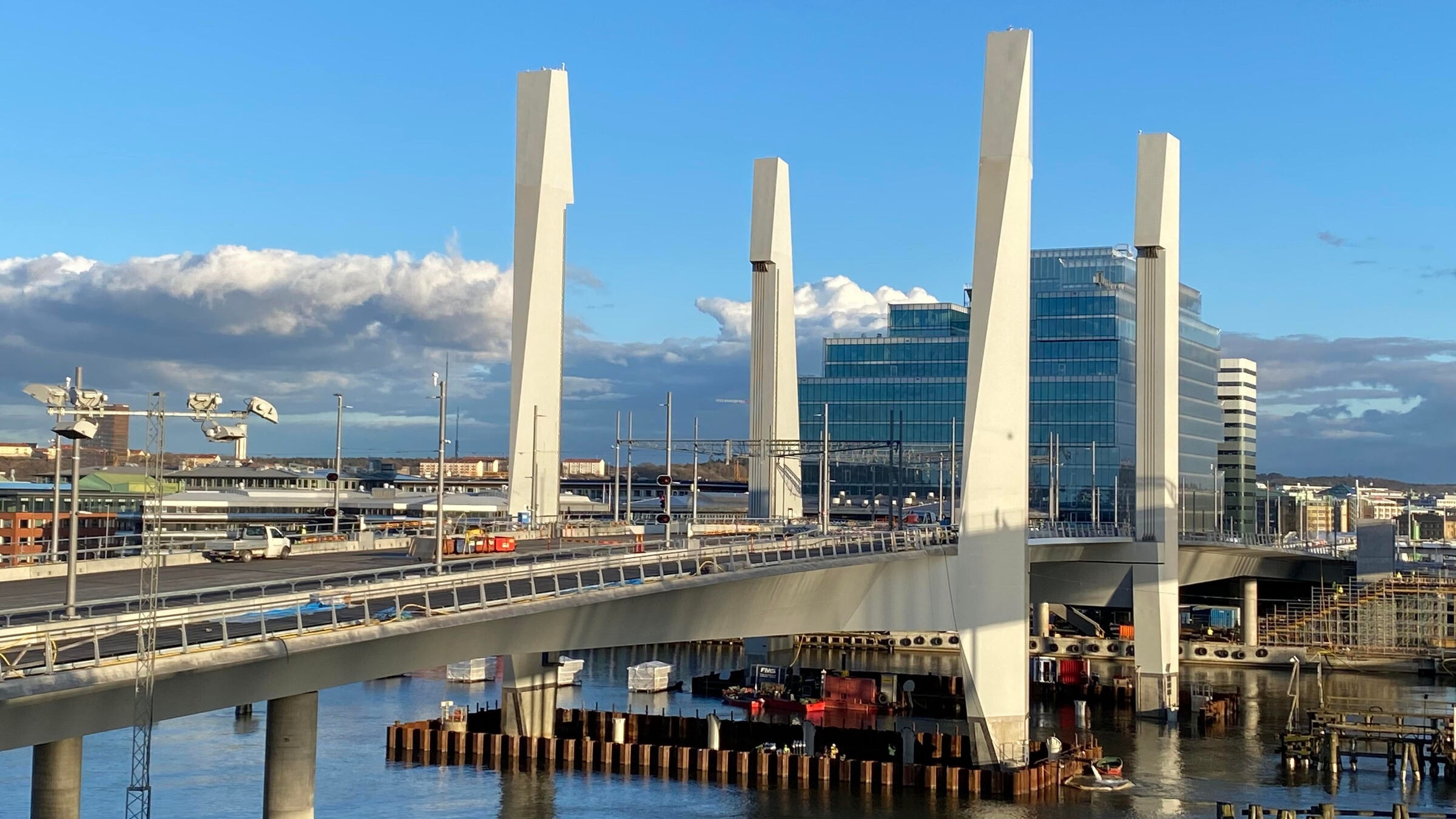 Hisingsbron is the new link between the mainland and Hisingen. It is a steel and concrete lift bridge. Modern cable-stayed bridge with tall white pylons spanning a river, set against a cityscape.