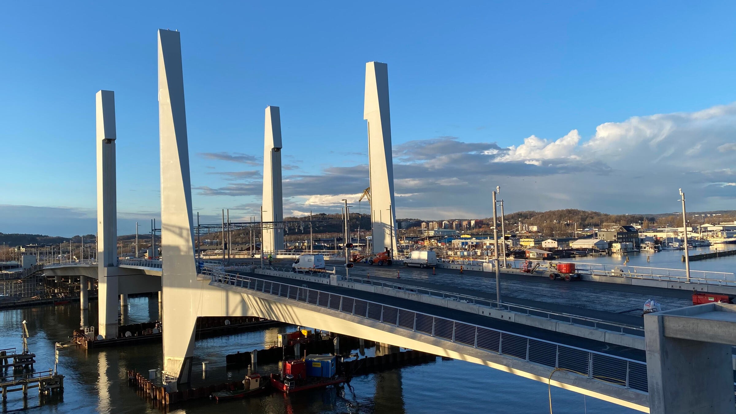 Modern cable-stayed bridge spanning over water with towering pylons against a blue sky backdrop.
