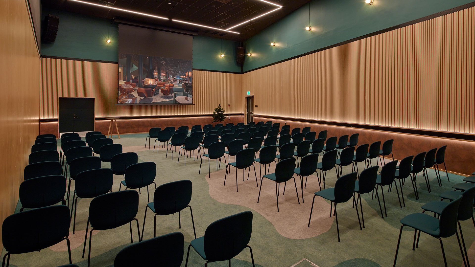 Large room with rows of chairs facing a big screen.