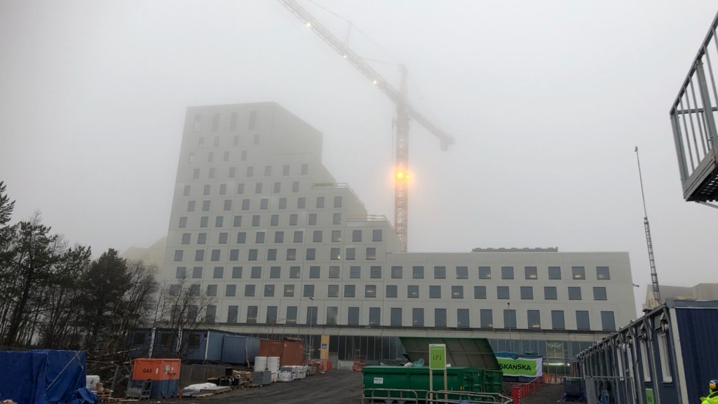 The hotel with a gigantic crane hovering over it on a foggy day.