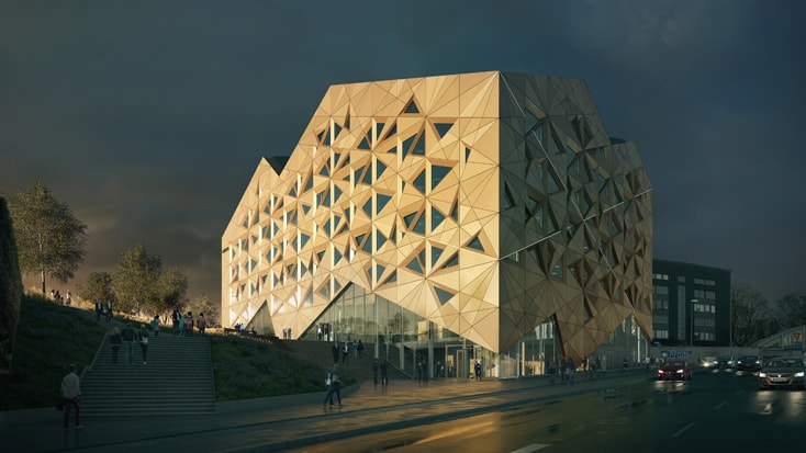 Modern building with a geometric facade illuminated at night, situated alongside a busy street.