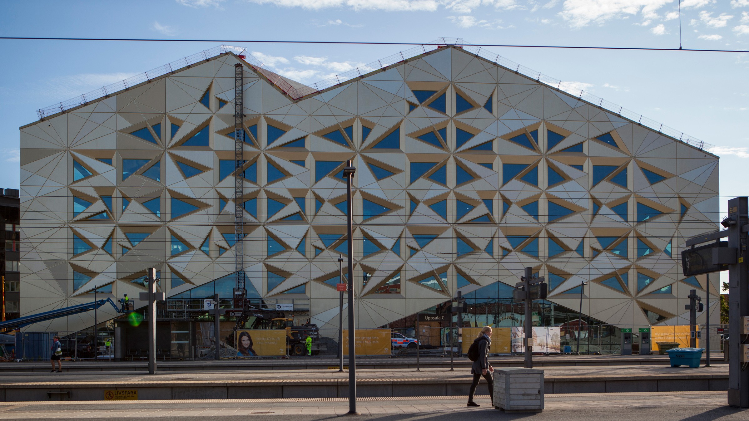Edificio moderno con patrones geométricos en la fachada y grandes ventanas bajo un cielo despejado.